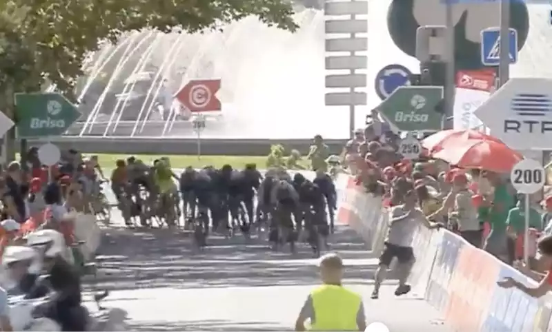 Athletes jump over barriers in the sprint finish of the Volta a Portugal.